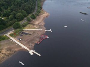 Drone view of a reservoir shoreline with docks, exposed banks, and waterfront property during low water conditions