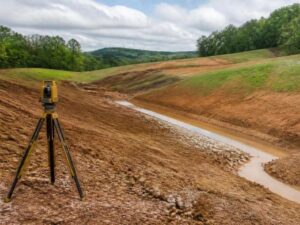 Topographic survey site in Pell City showing sloped ground and drainage patterns before repairs